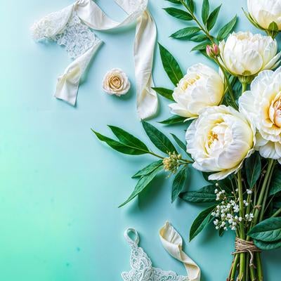 白とクリーム色の牡丹と薔薇、緑の葉と白いリボンのブーケの写真