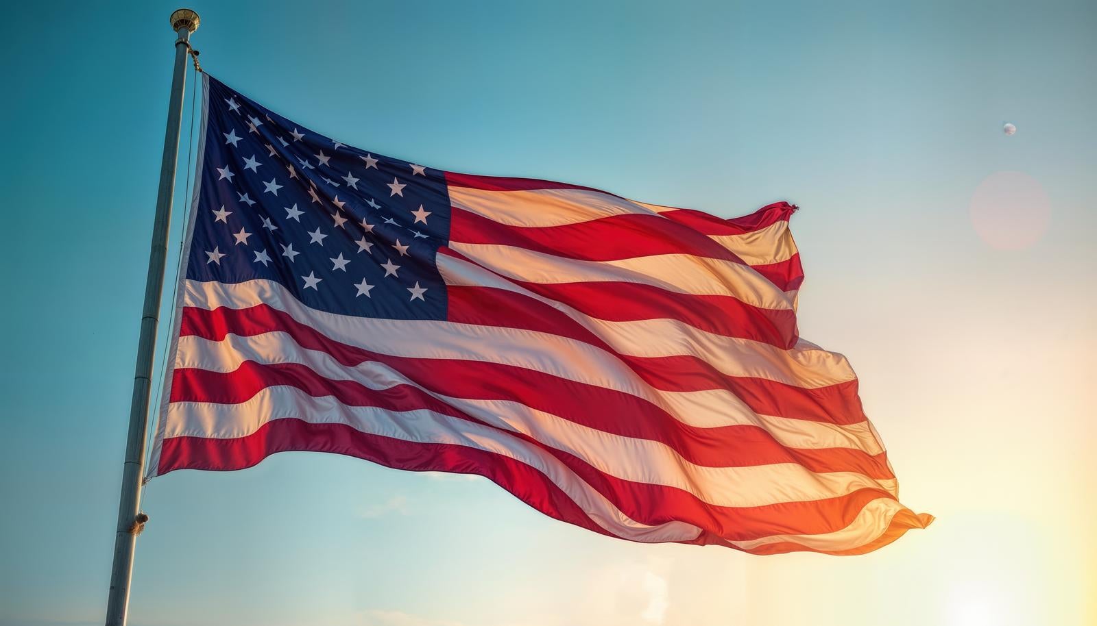 青空を背景に金属ポールから風になびく星条旗と赤白の縞模様