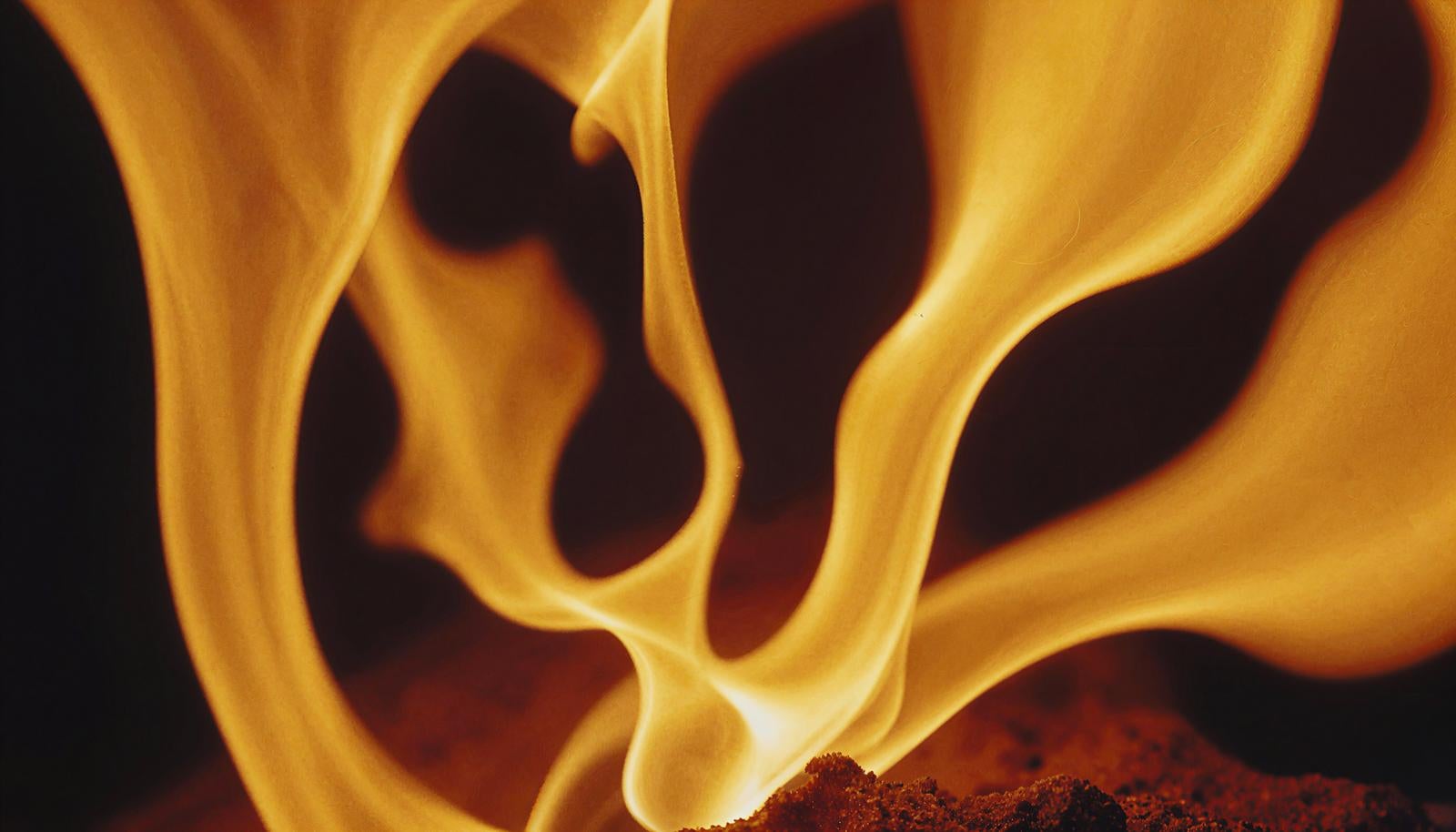 黄色と赤色が混ざり合う激しく燃える炎が黒い背景に舞い上がっている