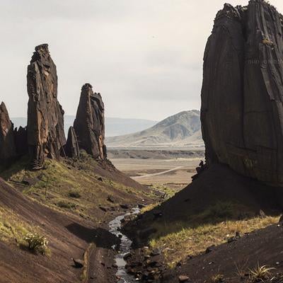 柱状節理の岩峰が立ち並ぶ火山地帯風の大地と渓流の写真