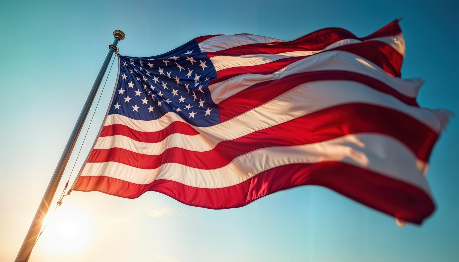 青空を背景にポールに掲げられた星条旗が風に大きくなびいている
