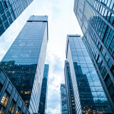 見上げたガラス張りの高層ビル群の写真