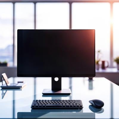 夕日が差し込むオフィスの電源が落ちたモニターの写真