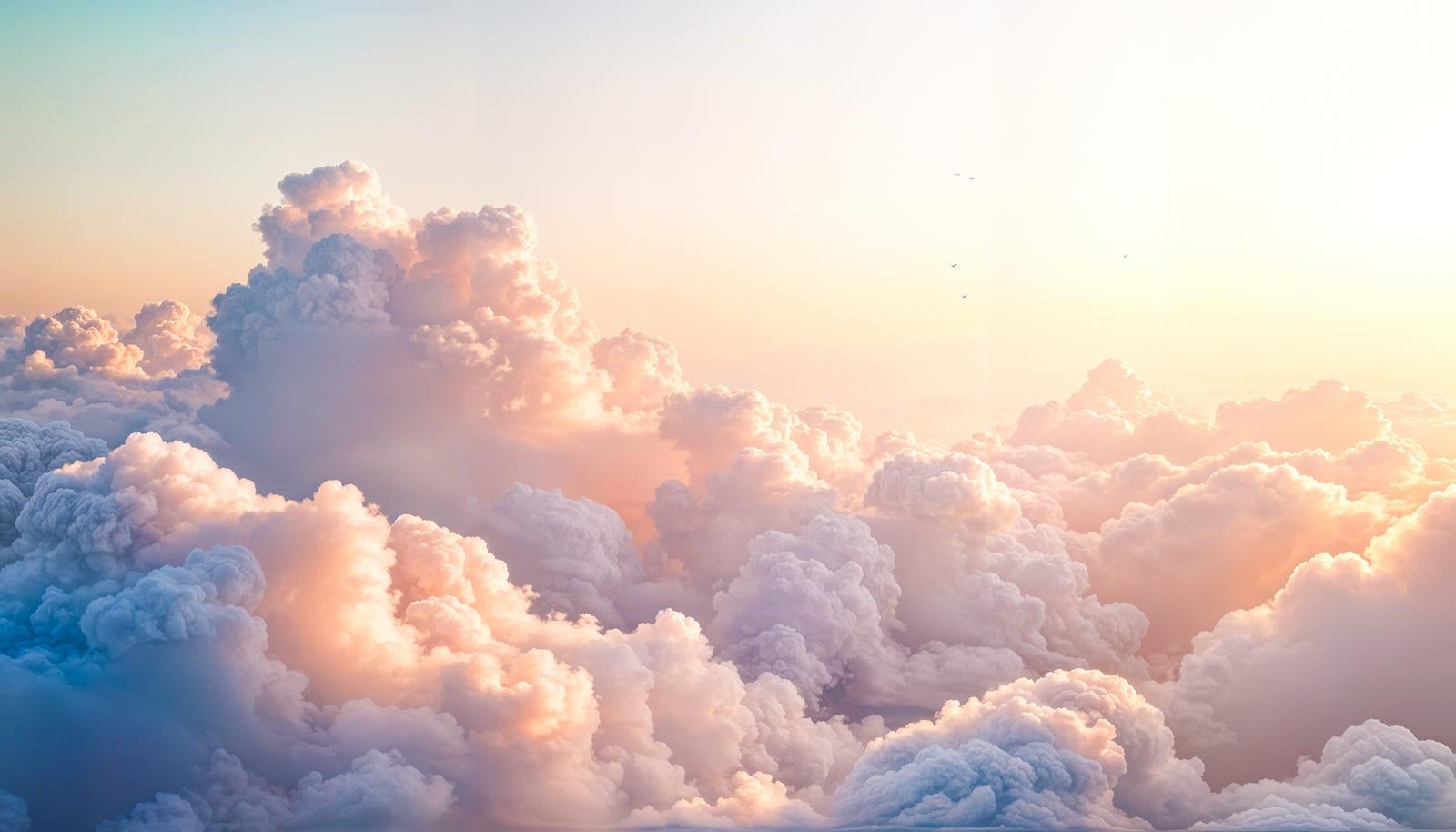 夕暮れの光でオレンジやピンクに染まった積雲の雲海を上空から見下ろした風景