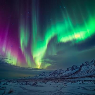オーロラが夜空を覆う雪山の冬景色の写真