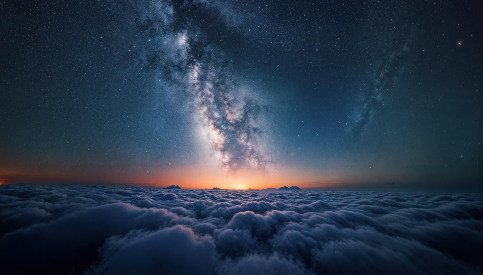 雲海の上に天の川が縦に伸びる満天の星空と地平線のオレンジ色の光