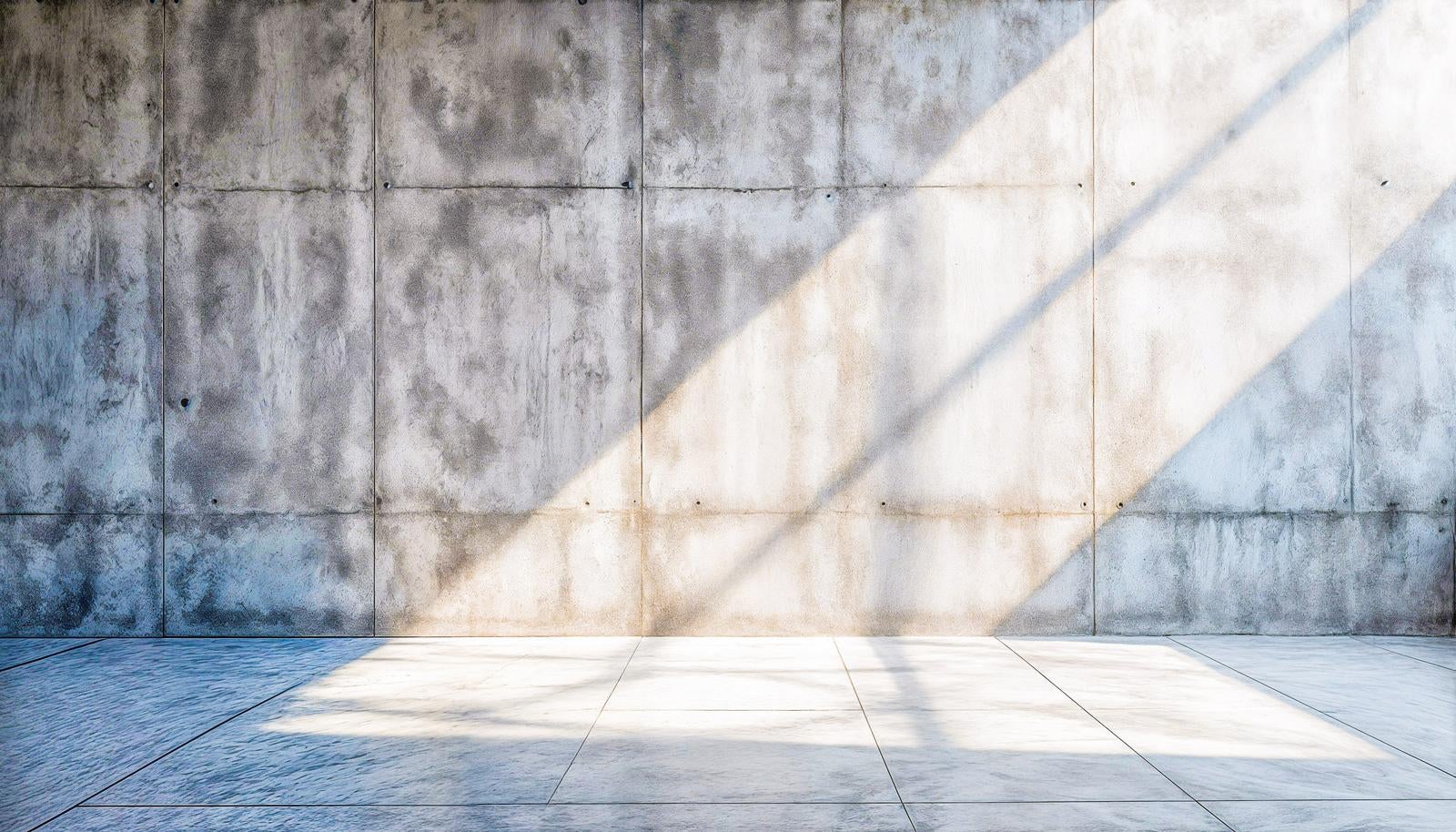 コンクリート打ちっぱなしの壁と床に右上から斜めの日差しが差し込んでいる