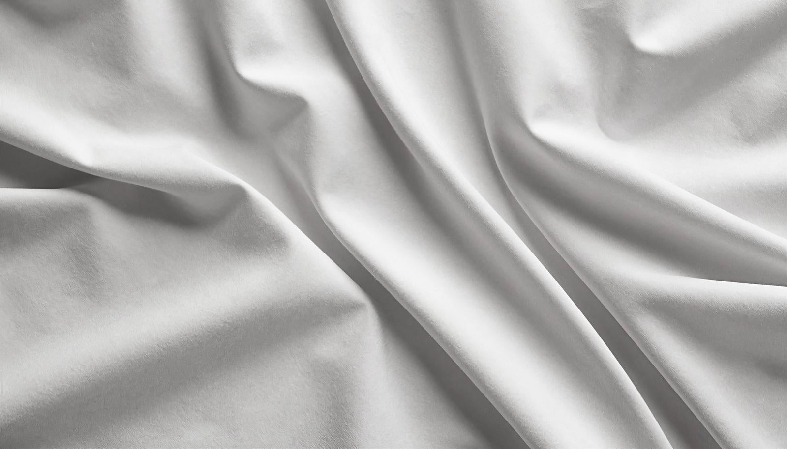 White linen-style fabric with multiple folds and wave-like wrinkles, with three-dimensional texture emphasized by light and shadow
