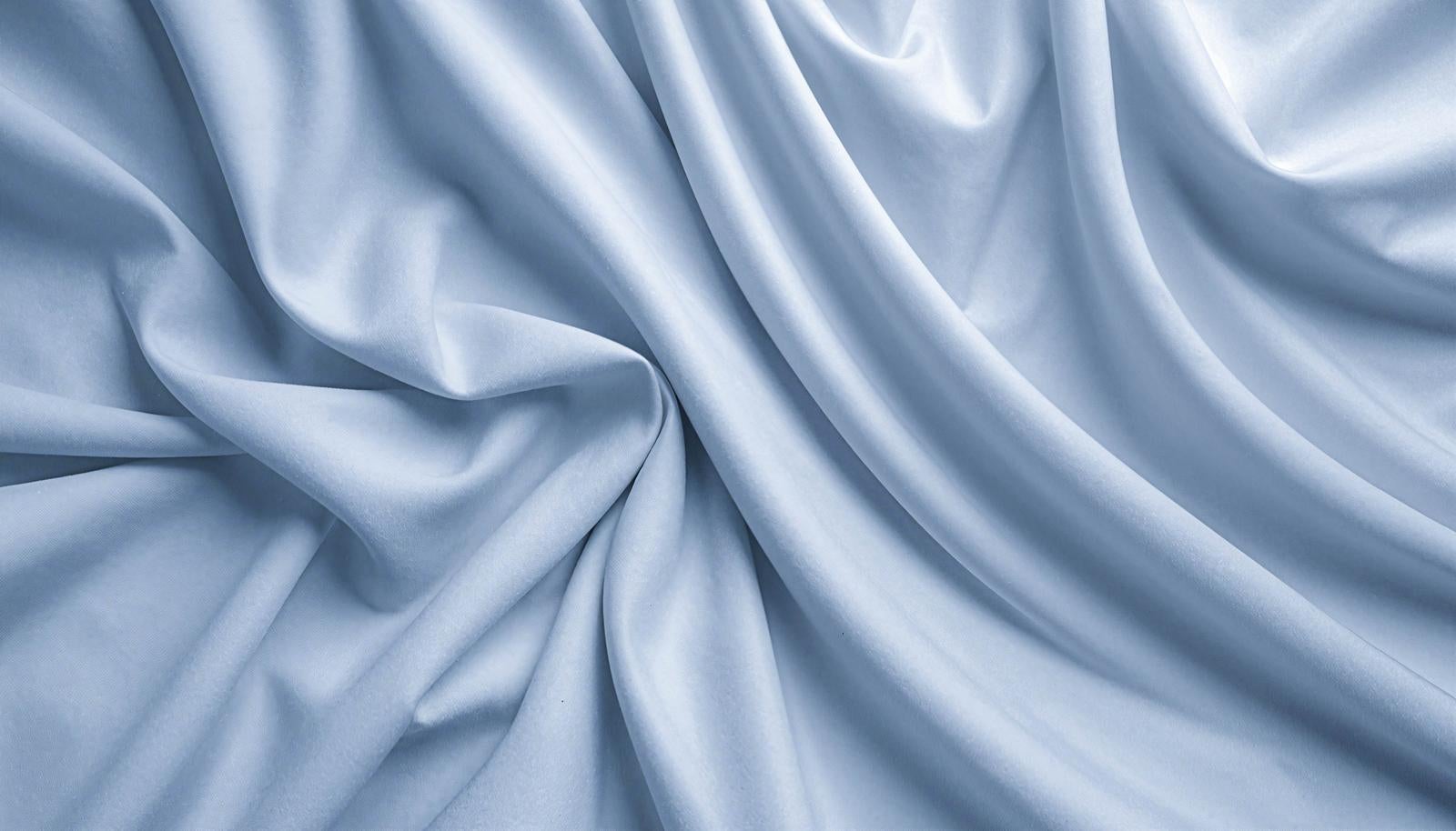 Pale bluish-white folded cloth fabric with light casting shadows, creating three-dimensional texture with prominent wrinkles and creases