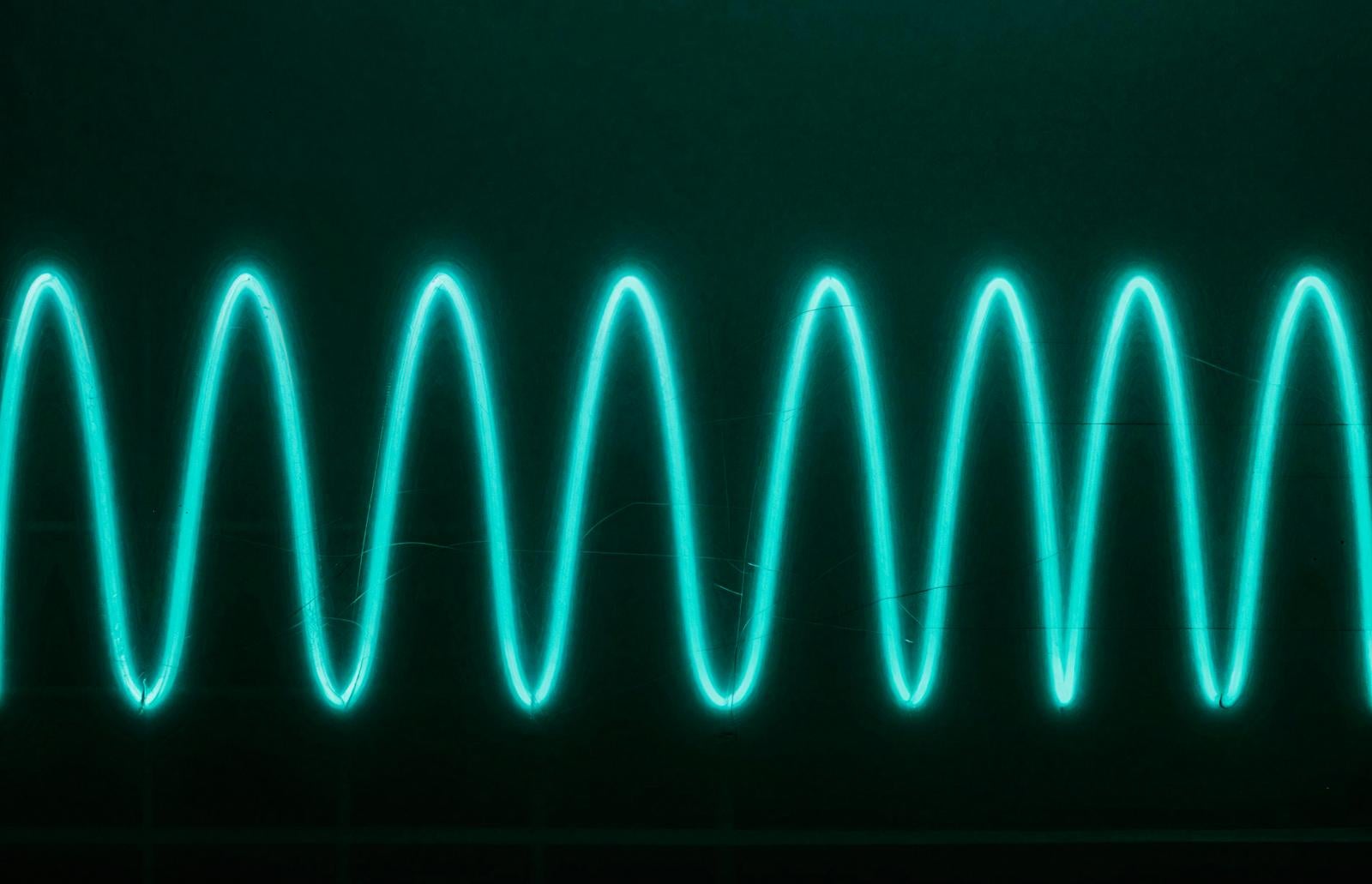 Eight cyan-green luminous waveforms arranged regularly and vibrating against a dark background
