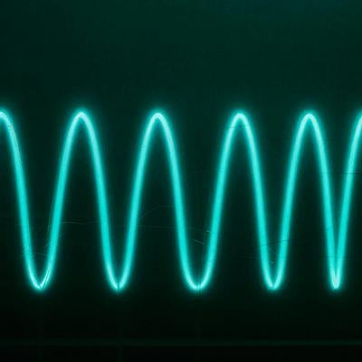 音波の振動を表現した青緑の発光波形の写真