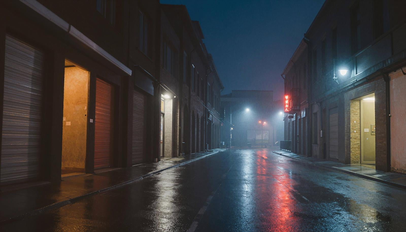 Wet nighttime street lined with shuttered buildings, red neon sign glowing in the distance