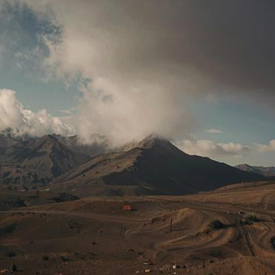 火山地帯の採掘作業と雲立ち込める山々の写真