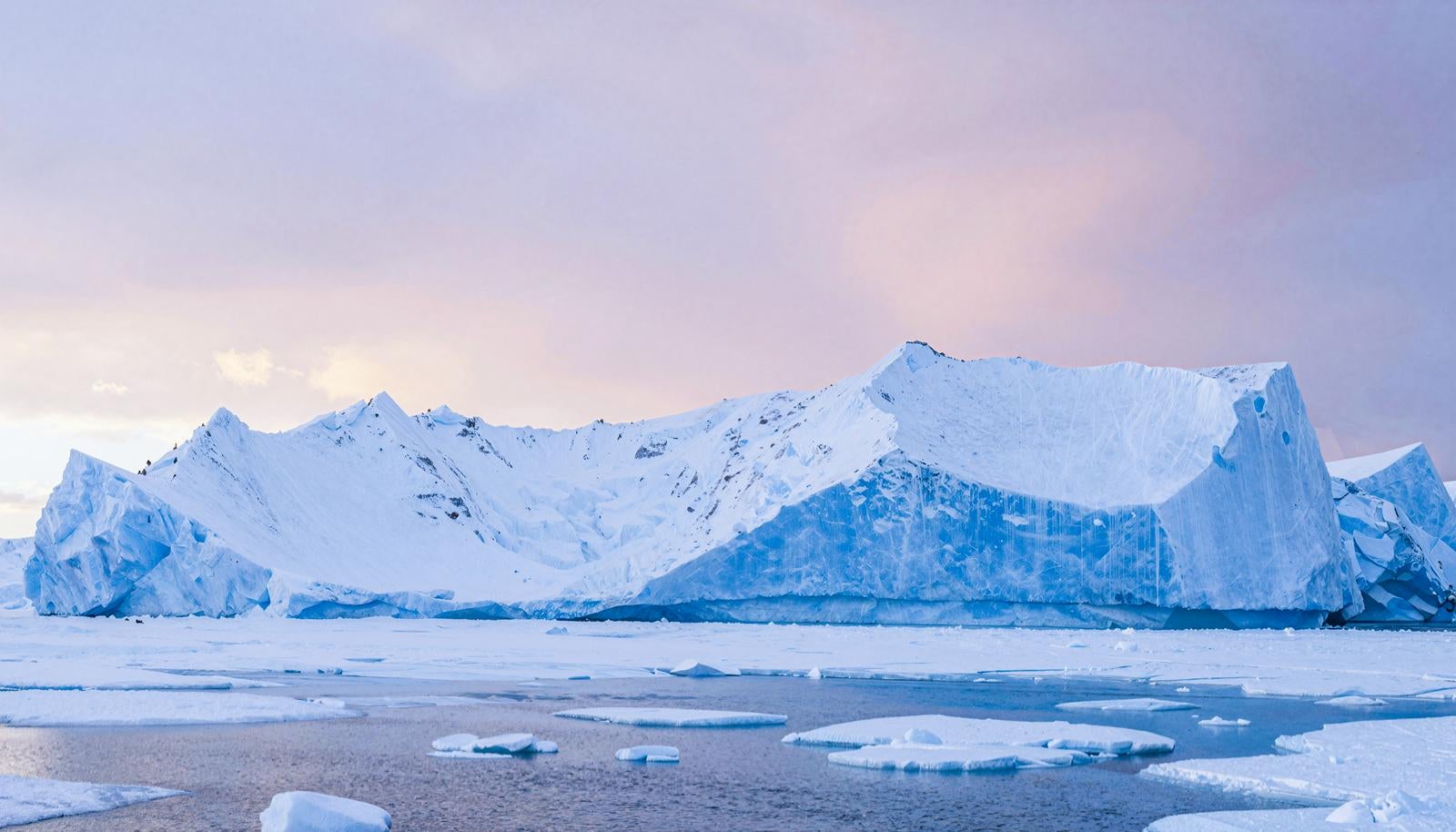 巨大な氷河の前に流氷が浮かぶ極地の海の風景