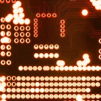 バックライトで光る電子回路基板のスルーホールの写真