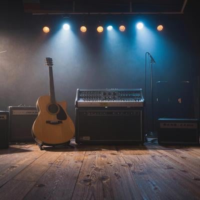 スタジオに置かれたアコースティックギターとアンプ類の写真