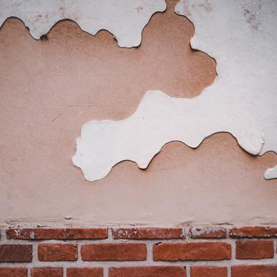 塗り壁が剥がれたレンガ塀の写真