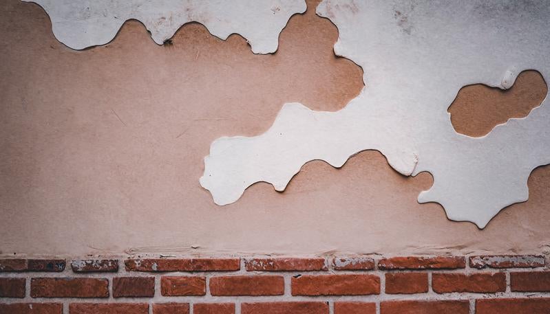 塗り壁が剥がれたレンガ塀の写真