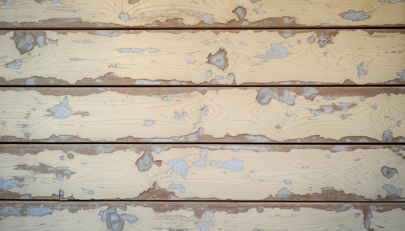 クリーム色の塗装が大きく剥がれて木目が露出した板壁のテクスチャー