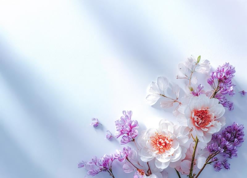淡い空色背景に白い牡丹風の花と紫のライラック風のフラワーアレンジメントの写真