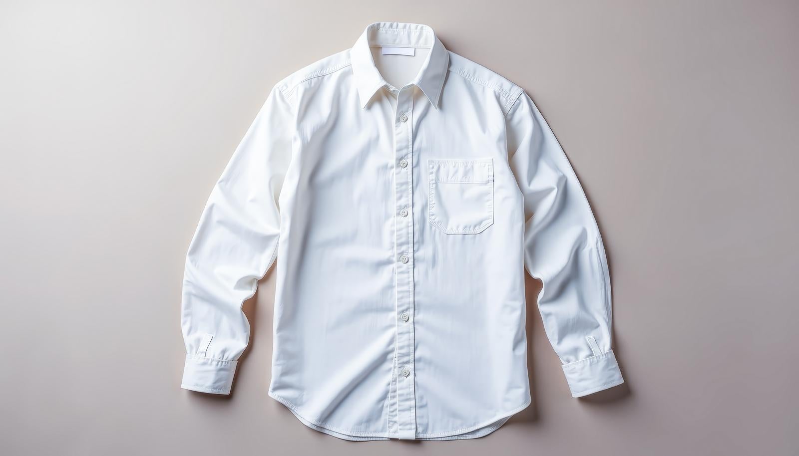 ベージュ背景の上に広げられた白い長袖シャツを真上から見たイメージ