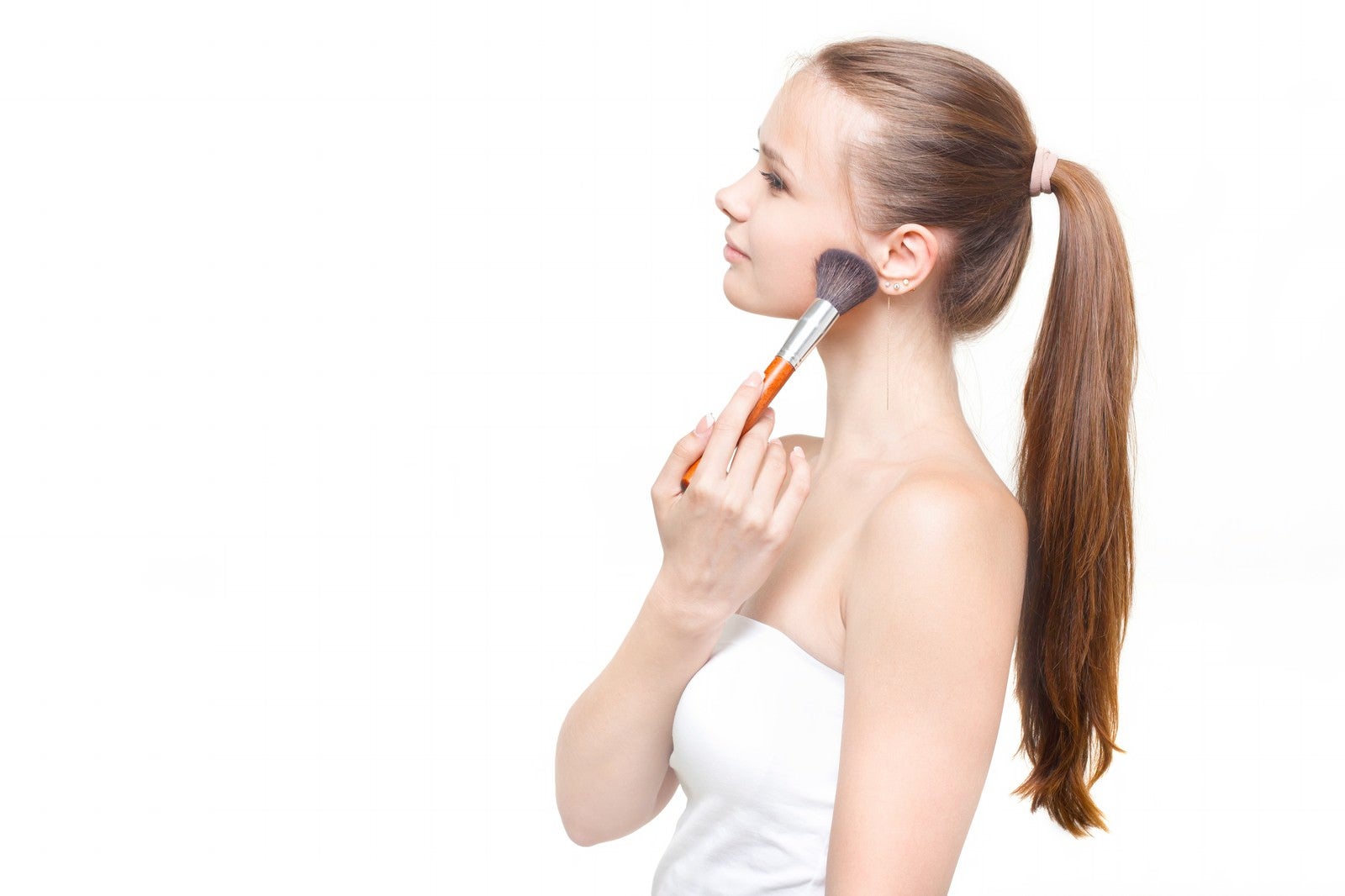 「顎にチークブラシを当てる横顔の外国人女性」の写真［モデル：モデルファクトリー］