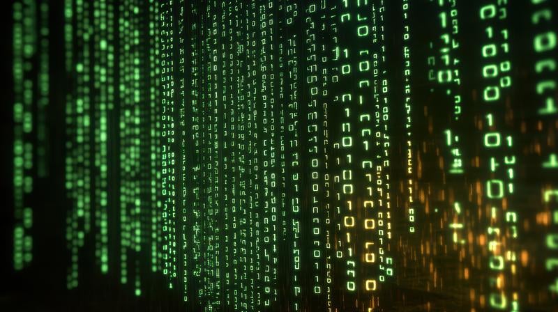 緑とオレンジのバイナリコードが流れる暗い画面の写真