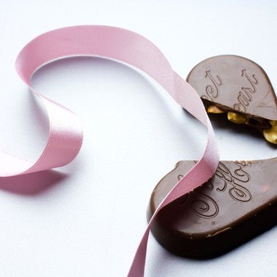 ピンクのリボンと割れたチョコレートの写真