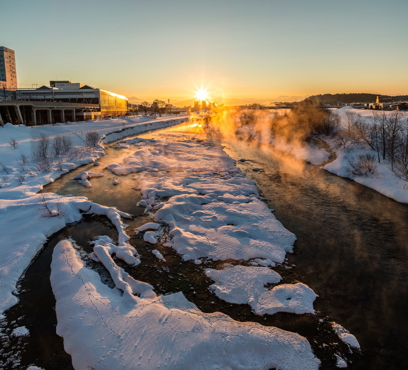 「冬の川から湧き上がる蒸気霧と朝日」の写真