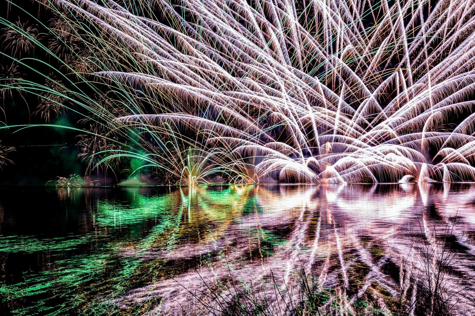 「湖面にリフレクションする水上花火（錦秋湖湖水まつり）」の写真