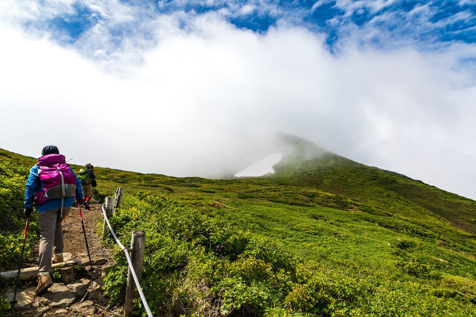 「沸き立つ雲の中へと進む登山者（秋田駒ヶ岳）」の写真