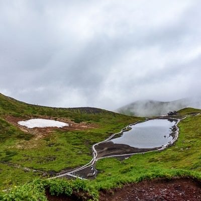 阿弥陀池と眼下に迫る雲（秋田駒ヶ岳）の写真