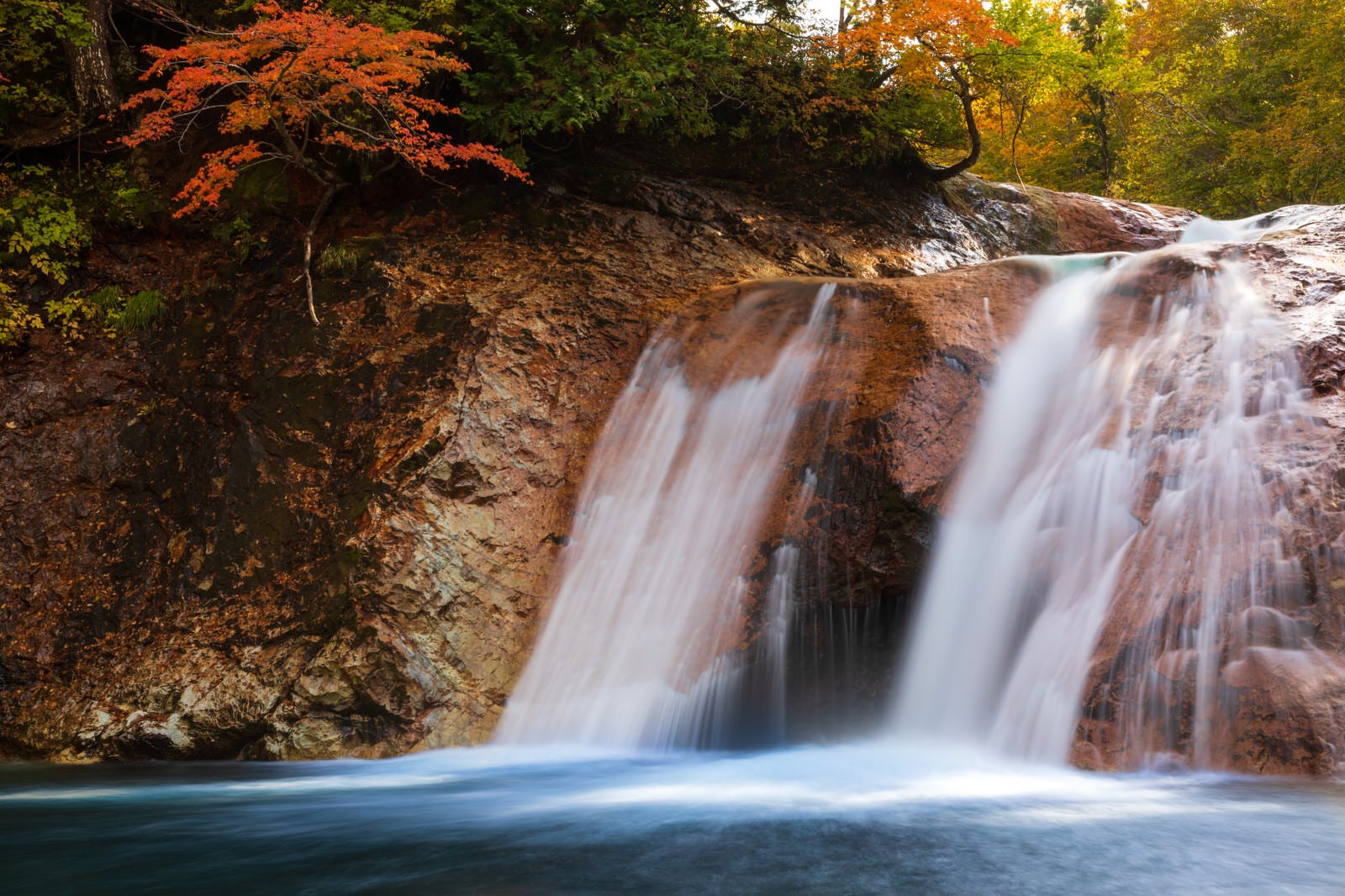 「紅葉と赤滝から落ちる水の流れ（秋田県雄勝郡東成瀬村）」の写真