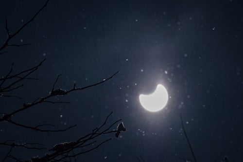 キラキラと反射する粉雪と日食の写真