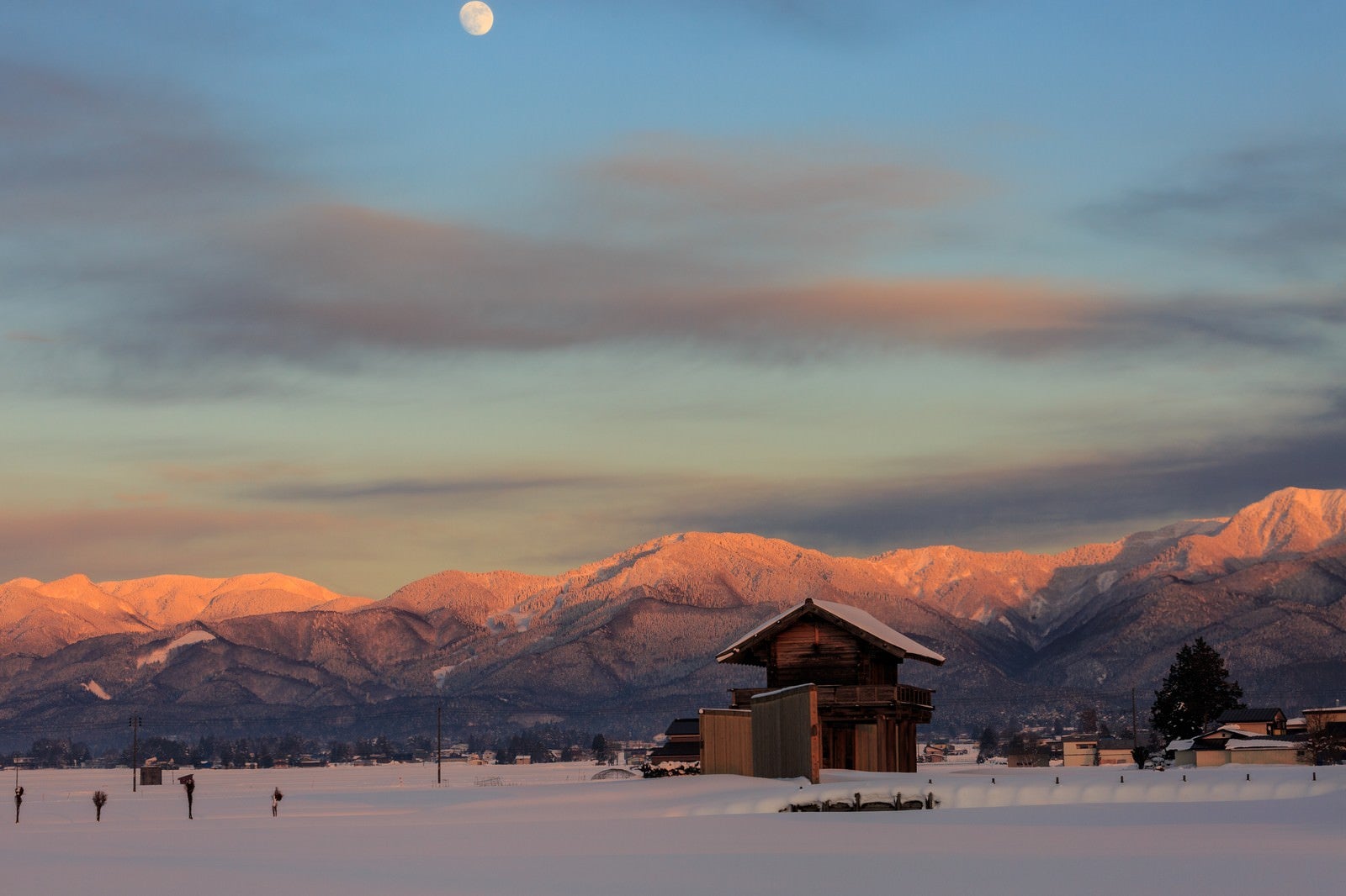 「雪に包まれた奥羽山脈と月」の写真