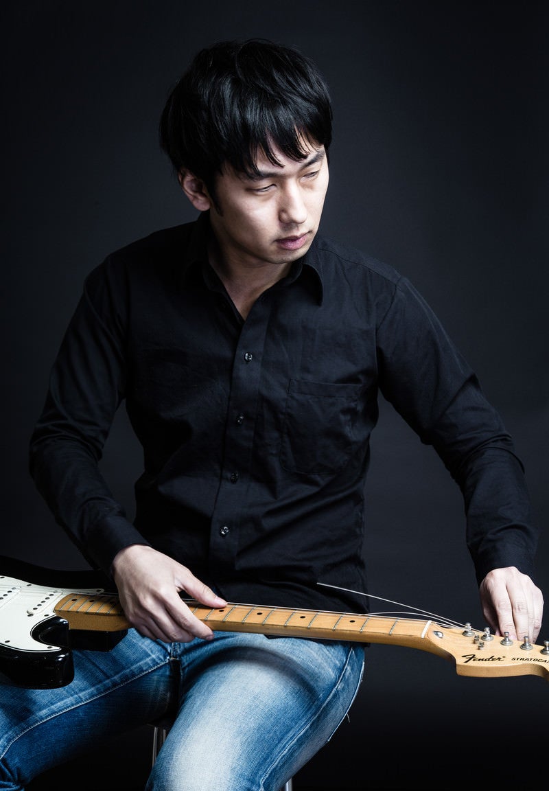 「ギターの弦を張り替えるギタリスト松野氏（仮）」の写真［モデル：大川竜弥］
