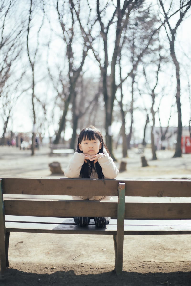 「公園のベンチで退屈そうにする少女」の写真［モデル：あんじゅ］