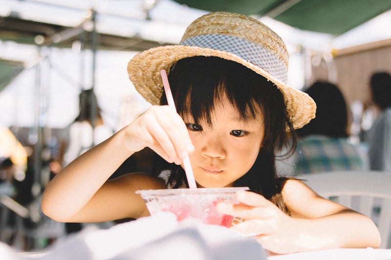 かき氷を食べる麦わら帽子の女の子の写真