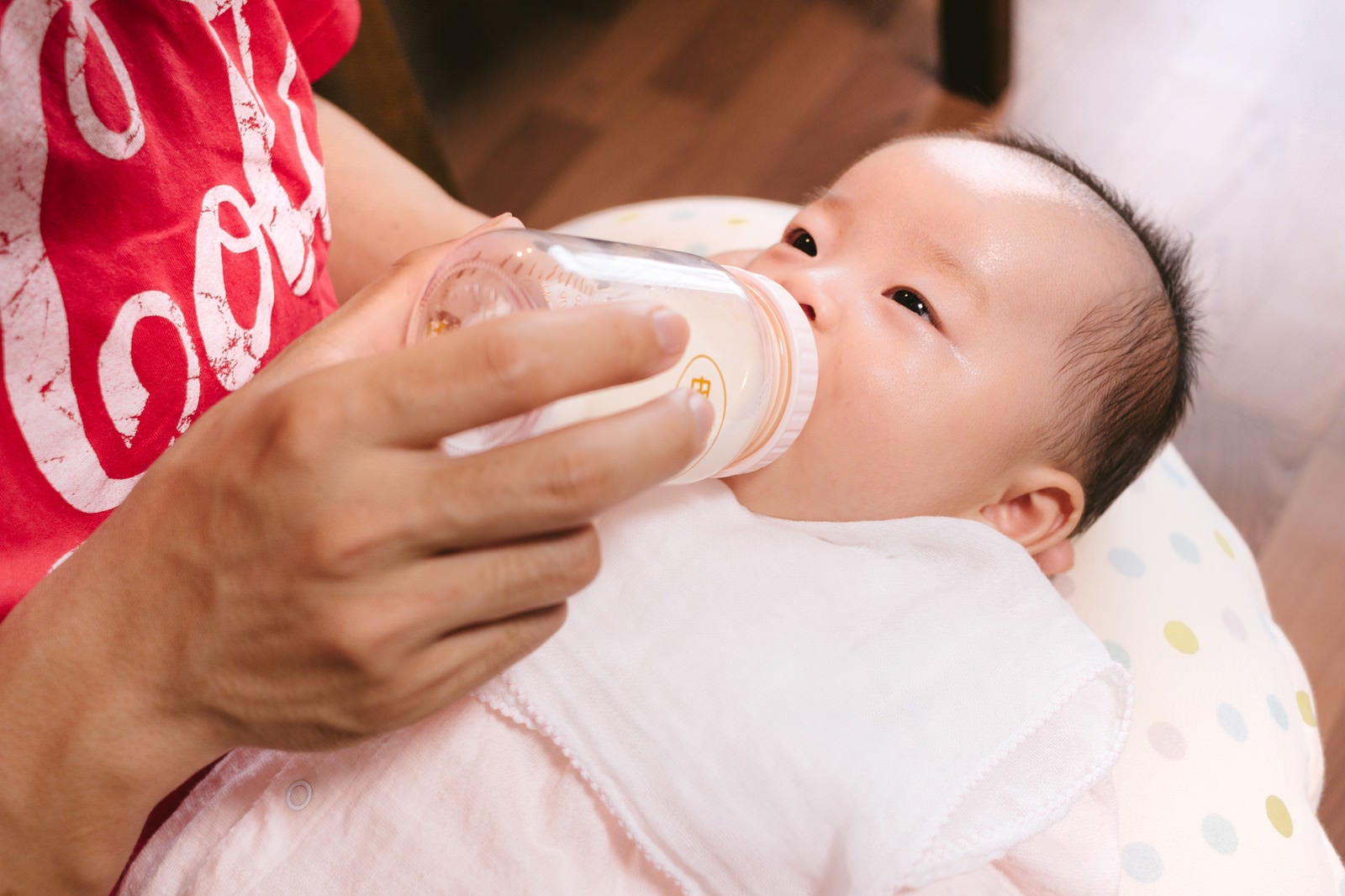 「哺乳瓶を咥える新生児」の写真