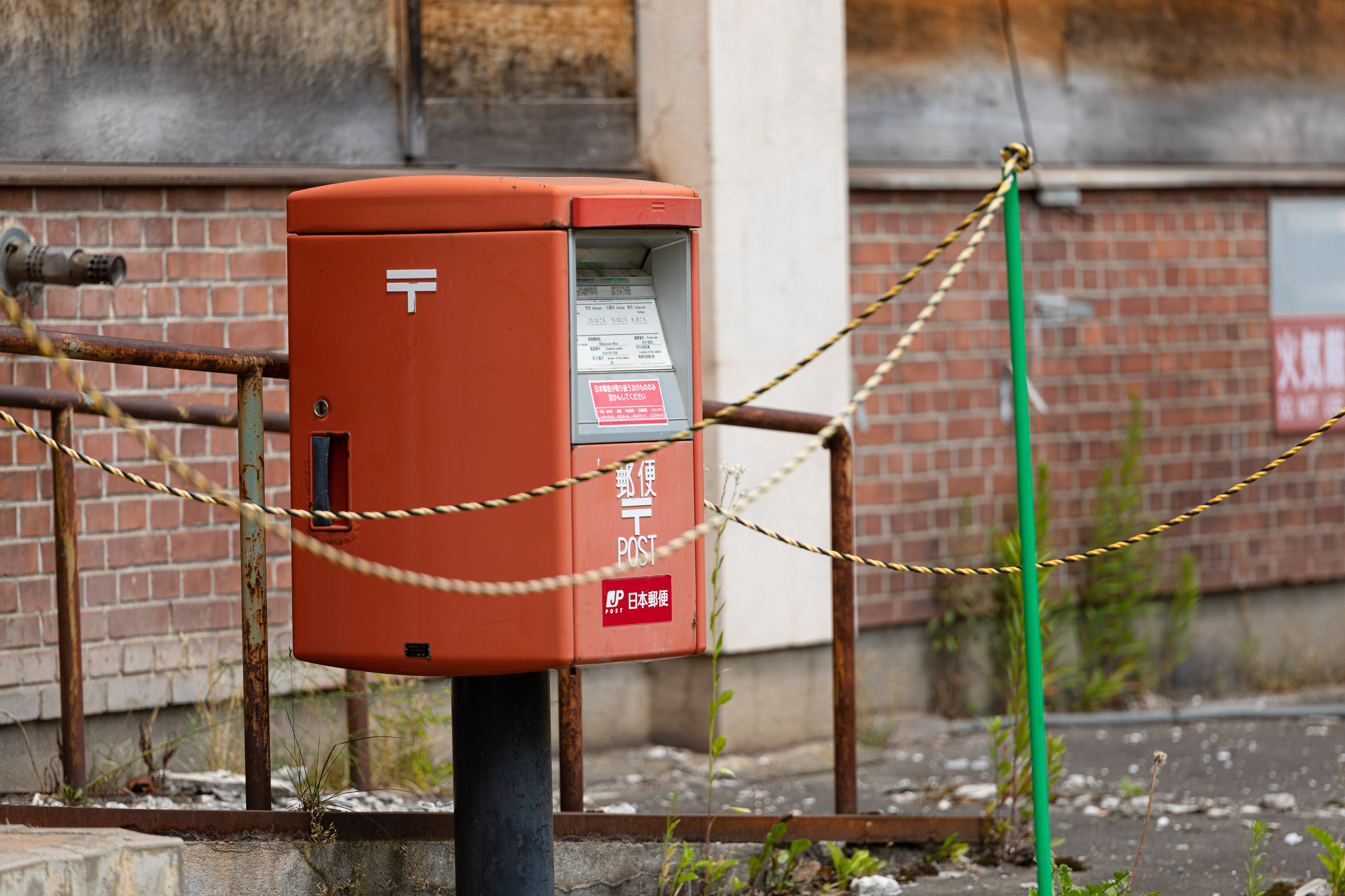 赤い郵便ポストと廃墟となった建物 - ぱくたそ