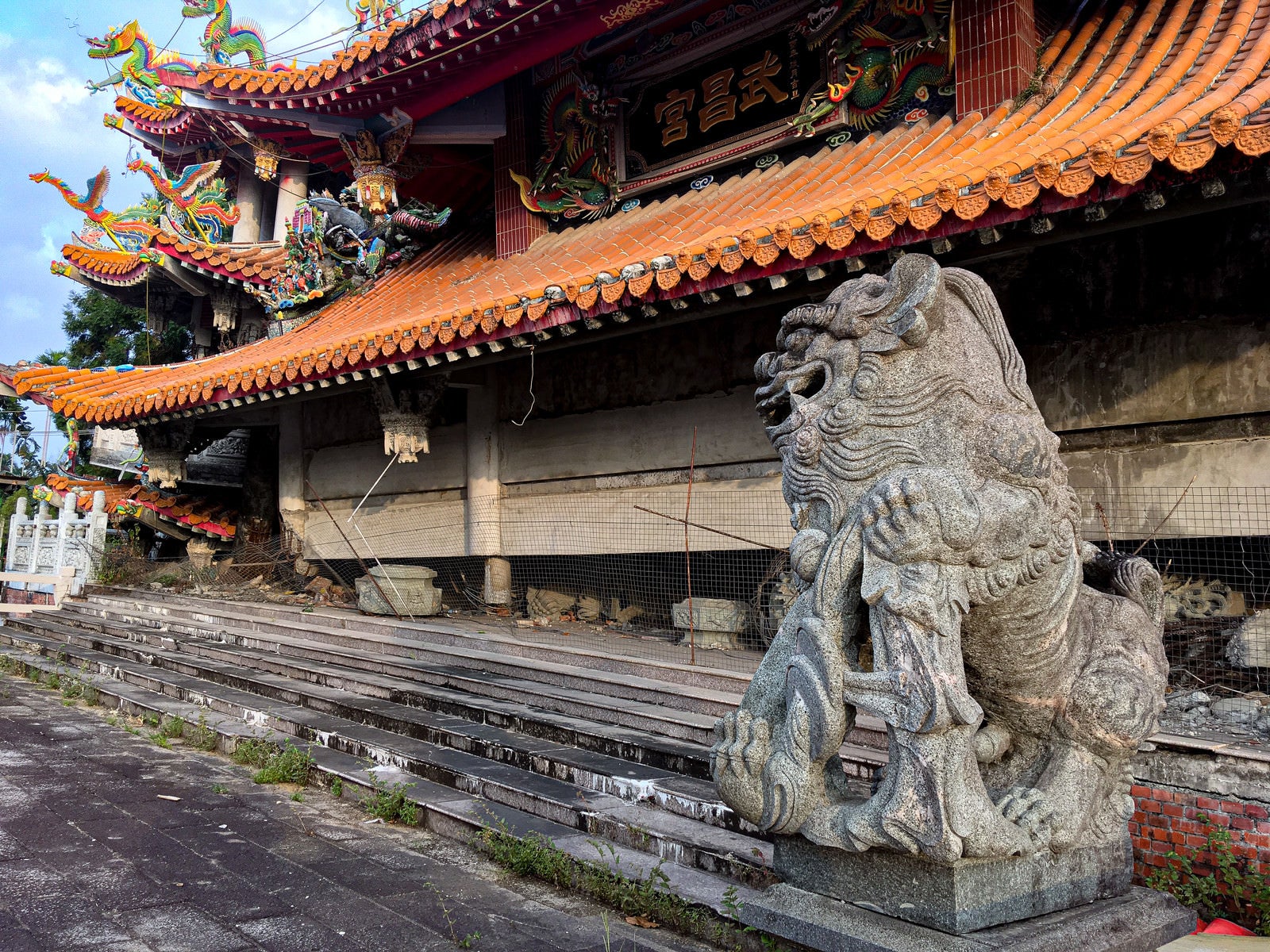 「地震で崩れた寺院に鎮座する狛犬の石像（台湾）」の写真