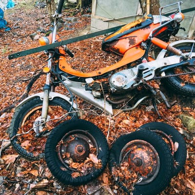 不法投棄されたバイクと複数のタイヤの写真