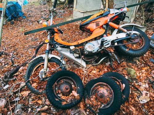不法投棄されたバイクと複数のタイヤの写真