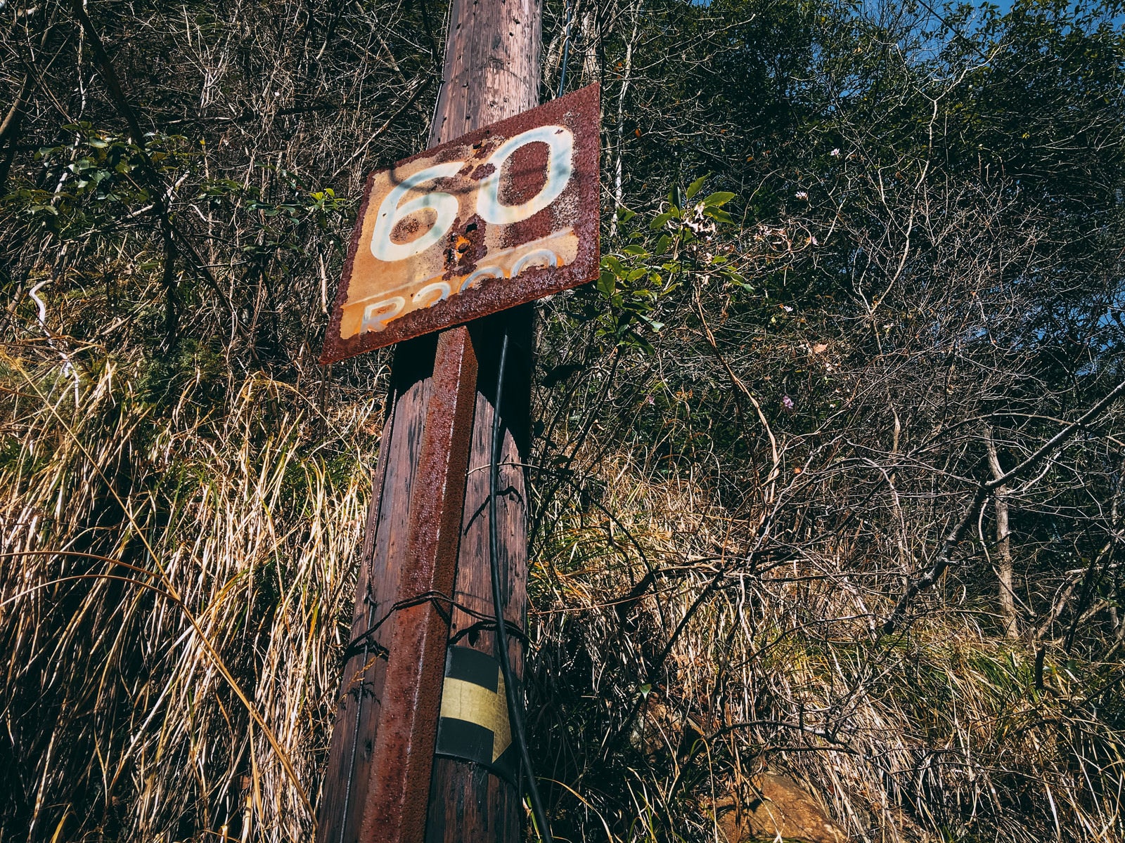 「60と書かれた錆びついた鉄看板（JR福知山線廃線敷）」の写真
