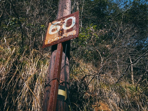 60と書かれた錆びついた鉄看板（JR福知山線廃線敷）の写真