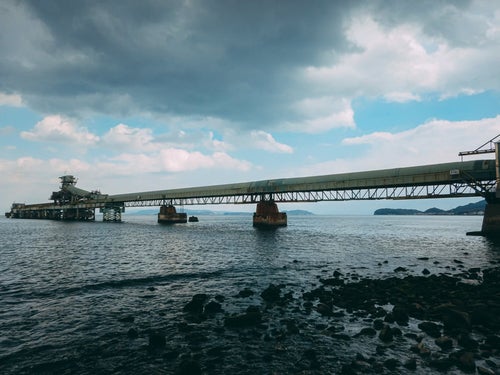 海の橋にかけた工場と雲の写真