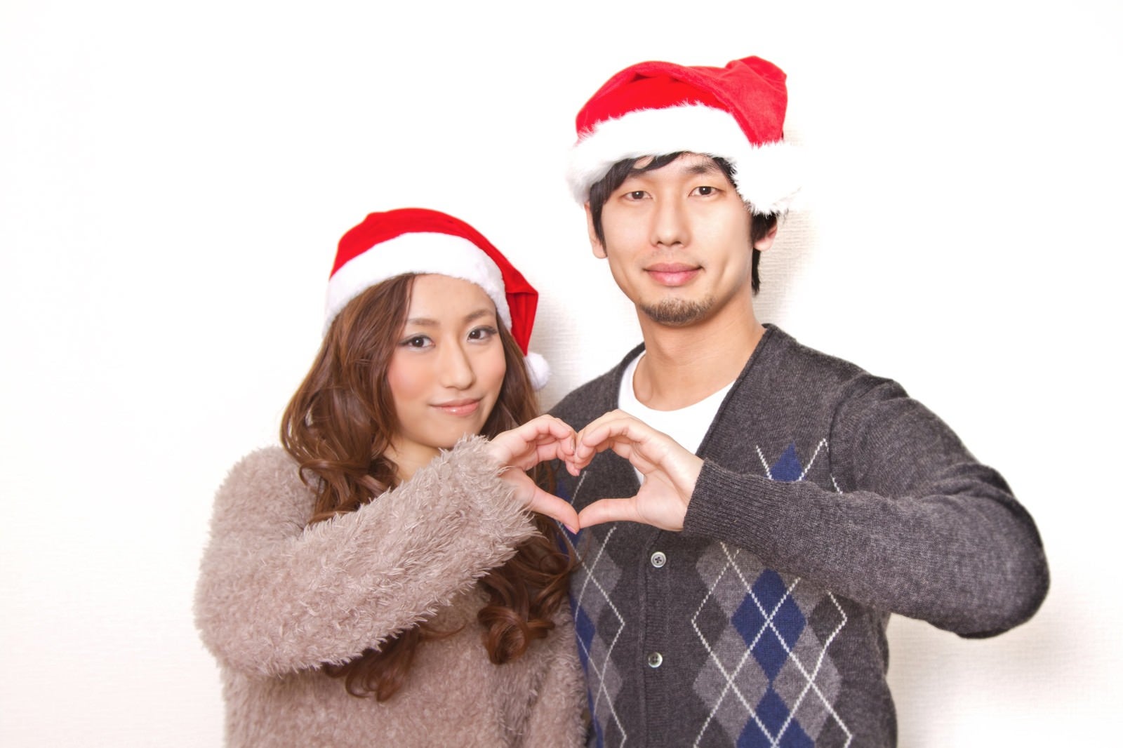 「クリスマスに指でハートの形を作る恋人」の写真［モデル：大川竜弥 北野佑々］