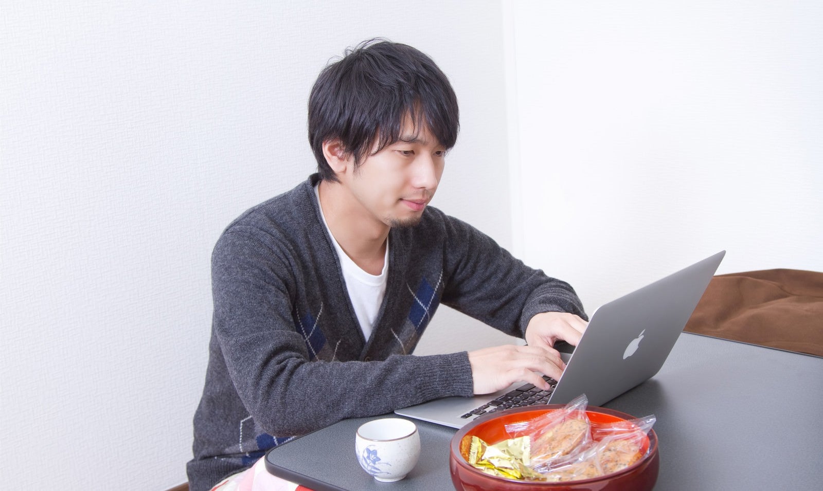 「こたつの上でパソコンを触る男性」の写真［モデル：大川竜弥］