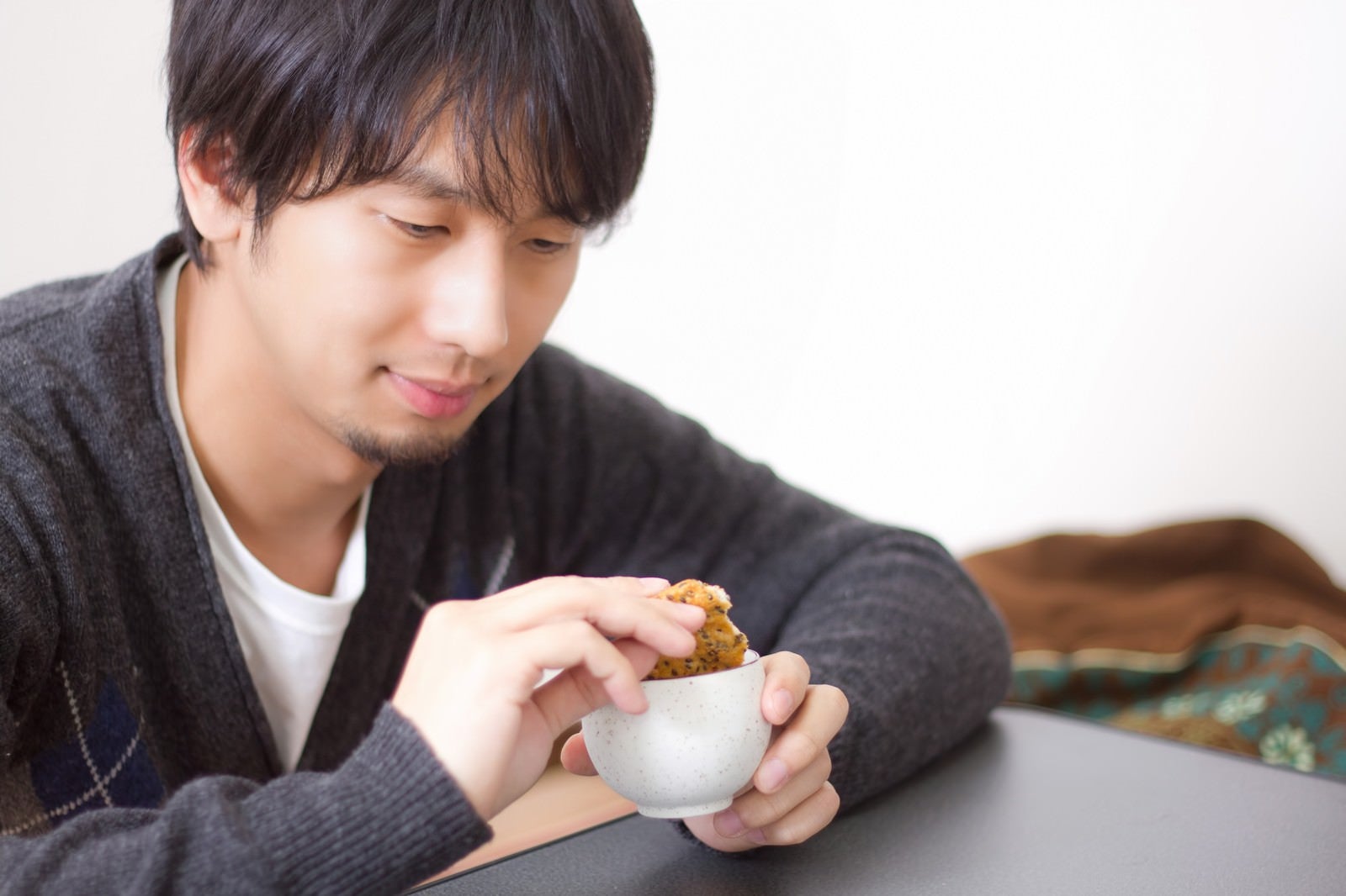 「せんべいをお茶につけてふやかす男性」の写真［モデル：大川竜弥］