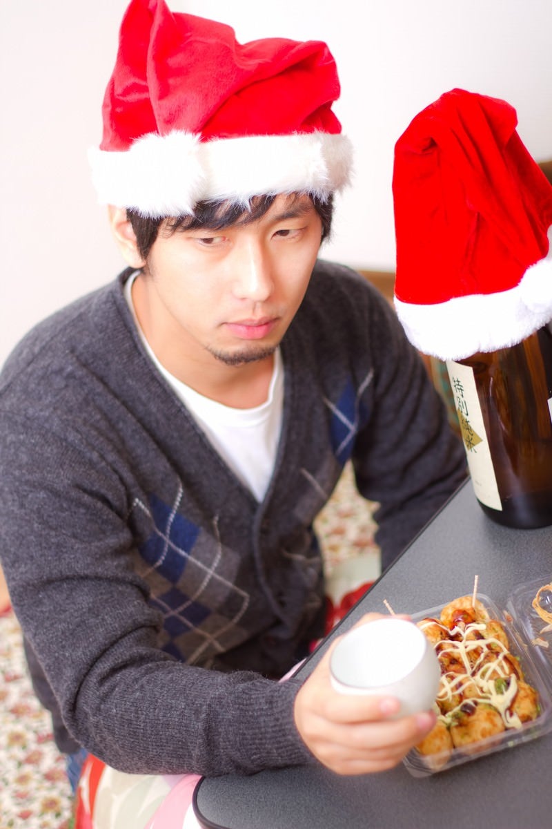 「孤独なクリスマスでもお酒とおつまみがあれば負けない！表情の男性」の写真［モデル：大川竜弥］